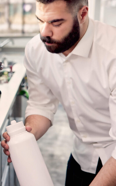 A barista in a white shirt inserts a filter for a professional espresso machine.