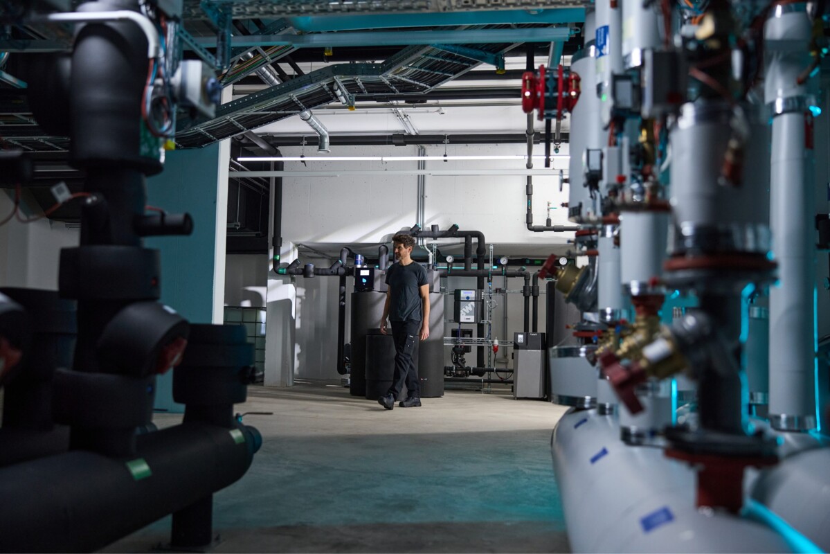 Ein Techniker inspiziert eine hochmoderne Wasseraufbereitungsanlage mit zahlreichen Rohrleitungen, Ventilen und Tanks.